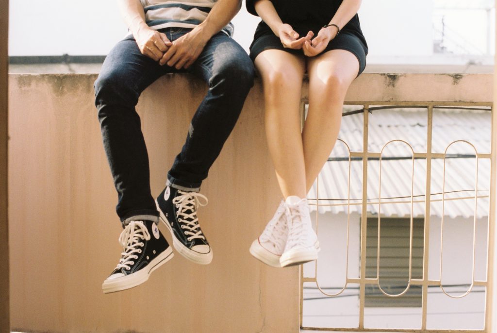 two people sitting on a wall
